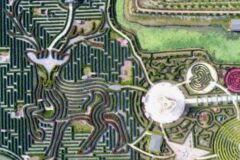 Aerial view of a geometric hedge maze with winding paths and central circular plaza featuring star and heart motifs.