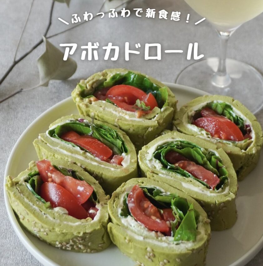 Five avocado rolls filled with tomato and greens on a white plate; Japanese text reads 'Avocado Roll' overhead.
