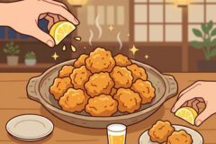 A large tray of crispy fried chicken bites being squeezed with lemon in a cozy dining room setting.