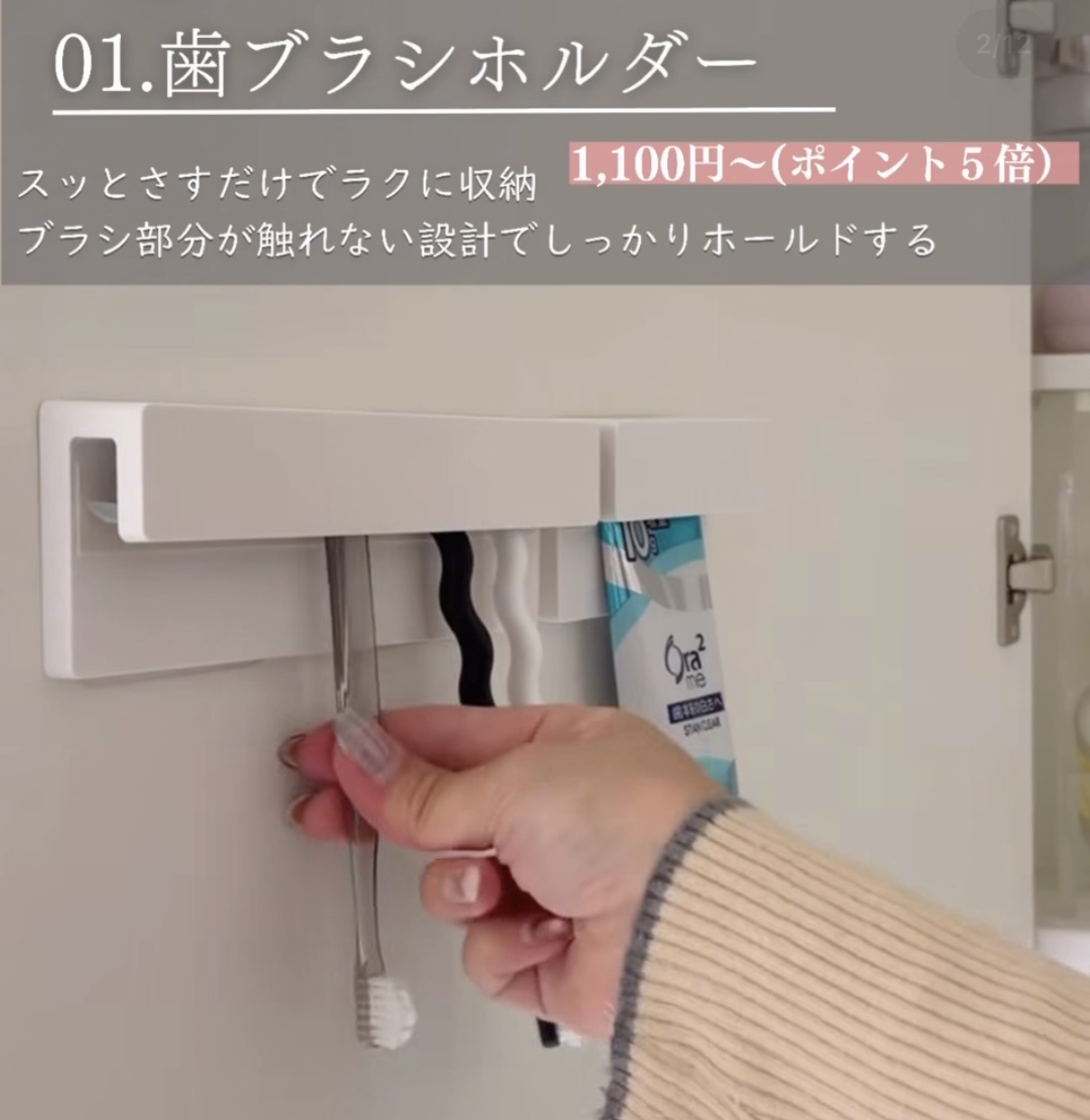 White wall-mounted toothbrush holder with several brushes stored, as a hand places one toothbrush into it beneath a cabinet door