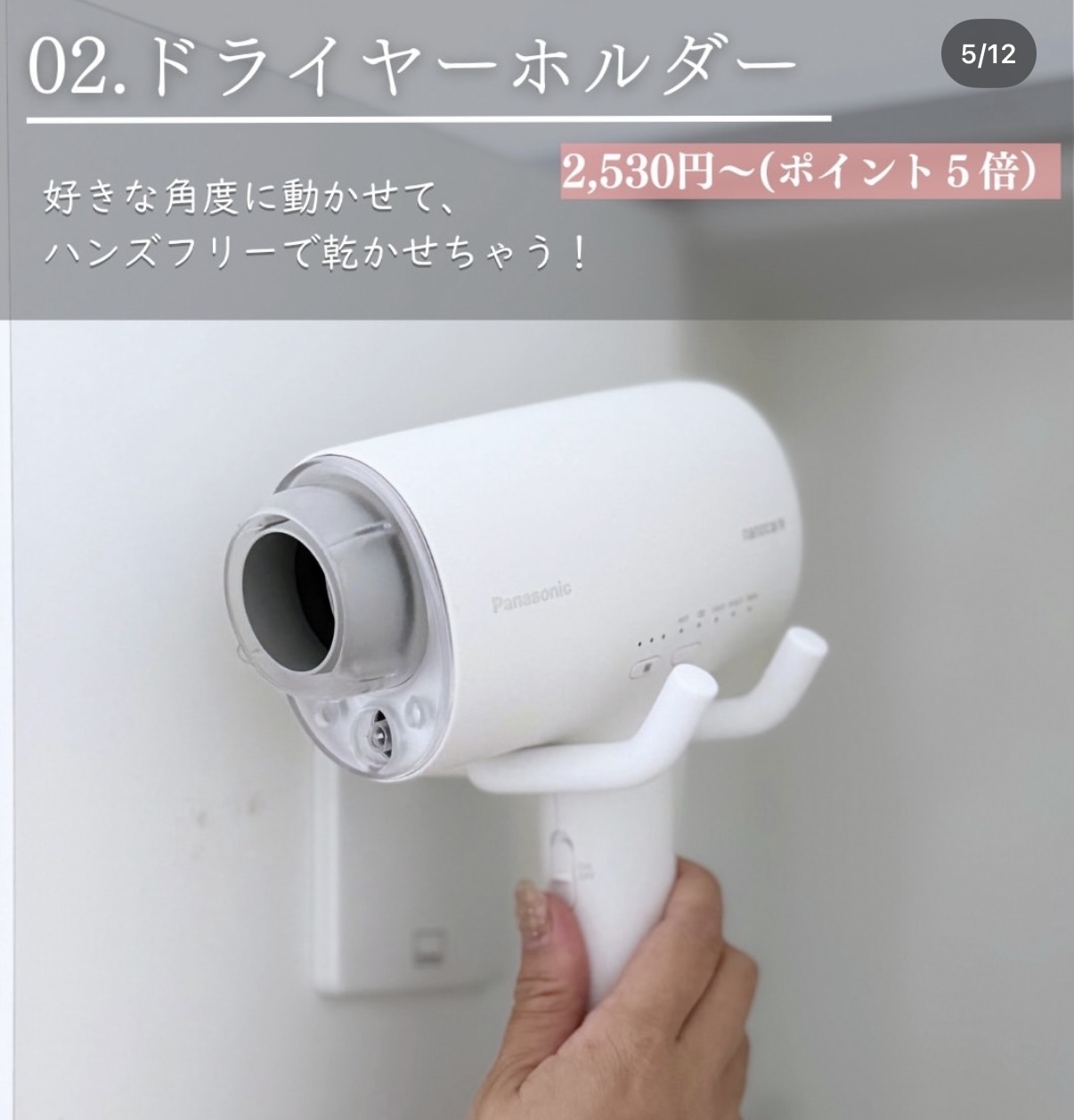 White Panasonic hair dryer mounted on a wall holder, hand gripping the handle; promotional banner with price text in Japanese.