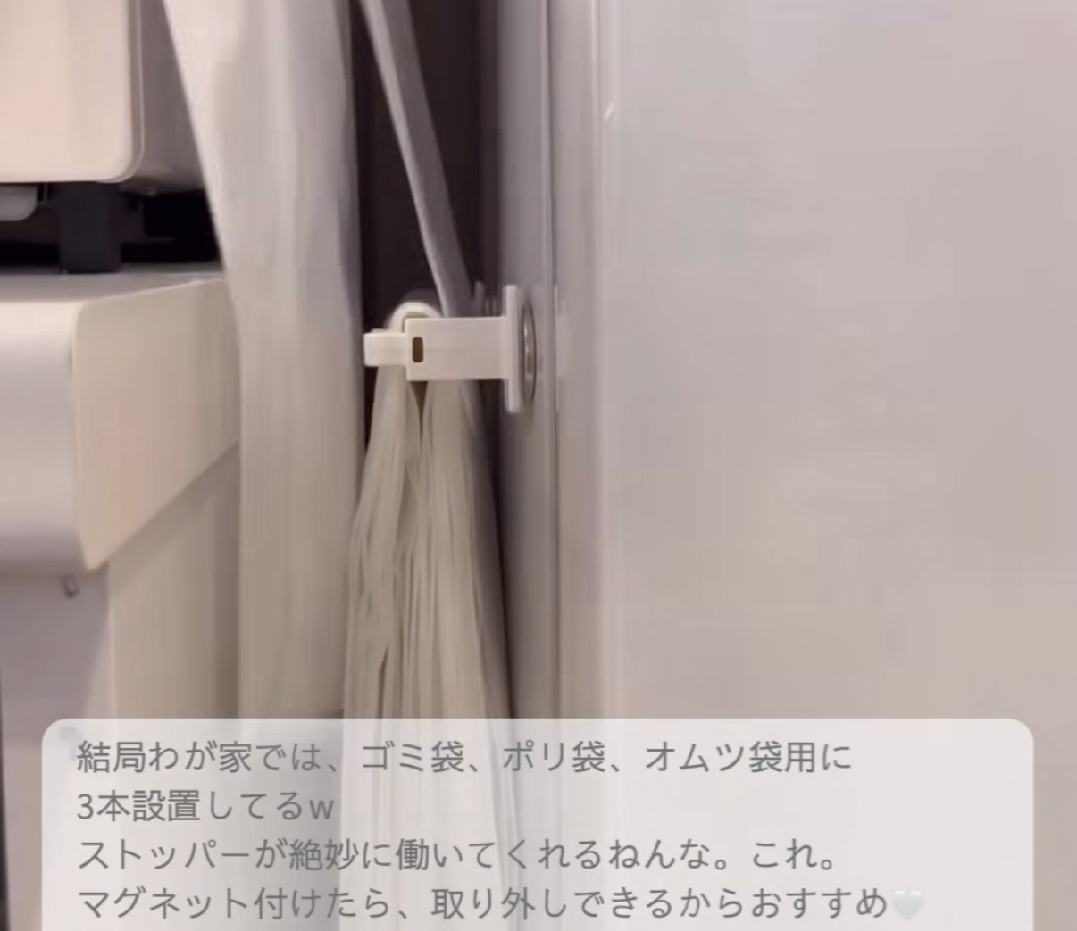 Close-up of a white plastic door‑edge latch holding a hanging bag in a narrow space.