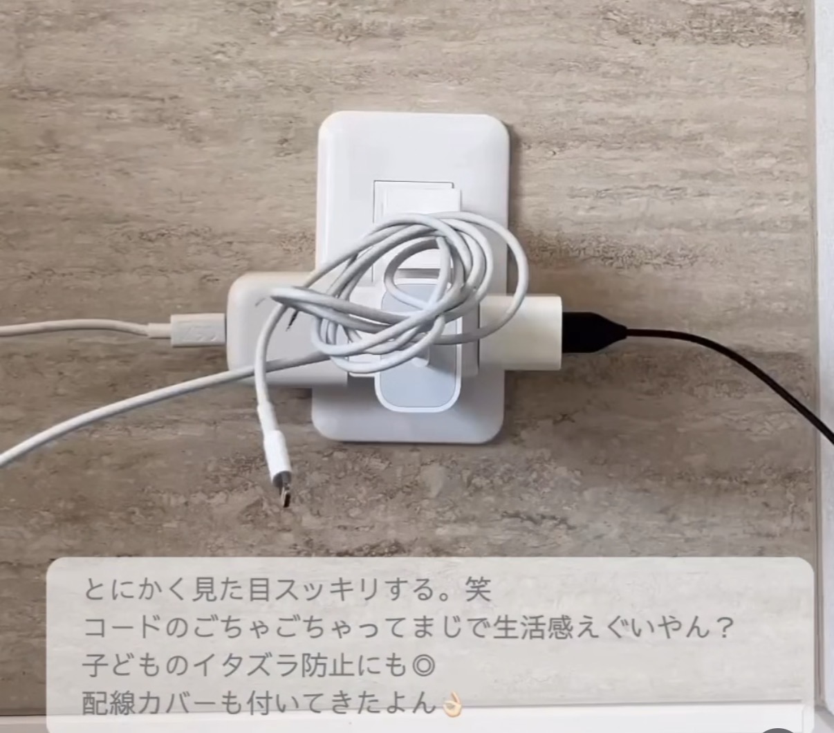 White wall outlet plate with a tangled bundle of charging cables, including a white USB-C/Lightning-style cable and a black power plug, resting on a light beige wall.