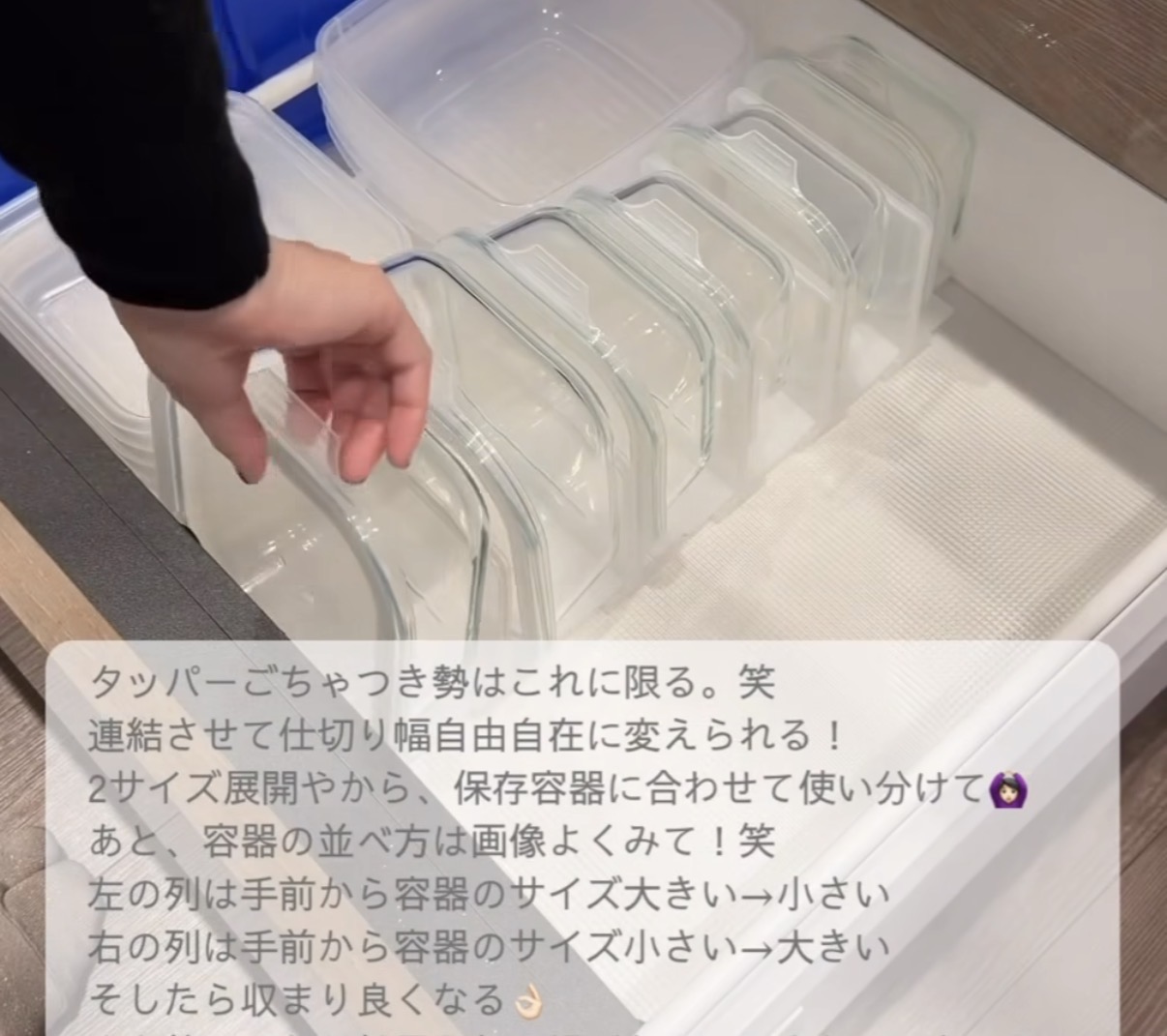 A hand arranges clear rectangular plastic food storage containers with matching lids standing upright in a drying/organizing rack.