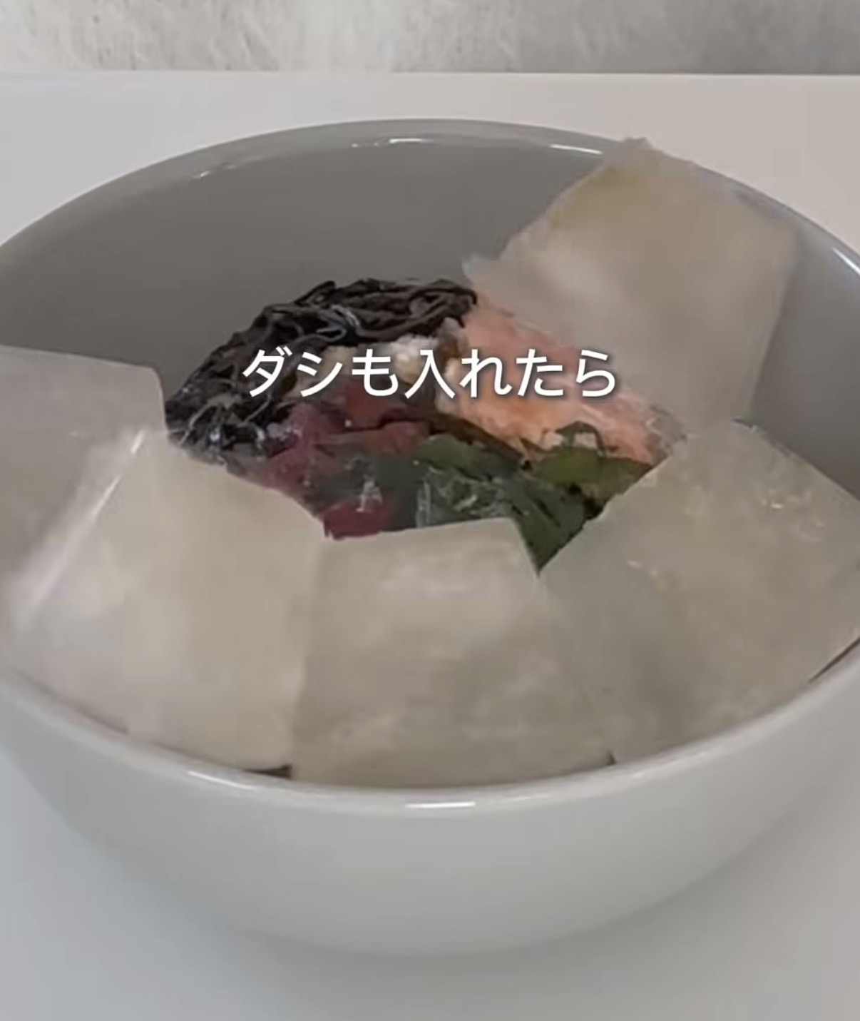 Screenshot | GLAM(グラム)|自分らしく生きる女性に、1日1GLAMを。 Bowl with assorted ingredients (seaweed, greens, pink items) and a Japanese caption about adding dashi.