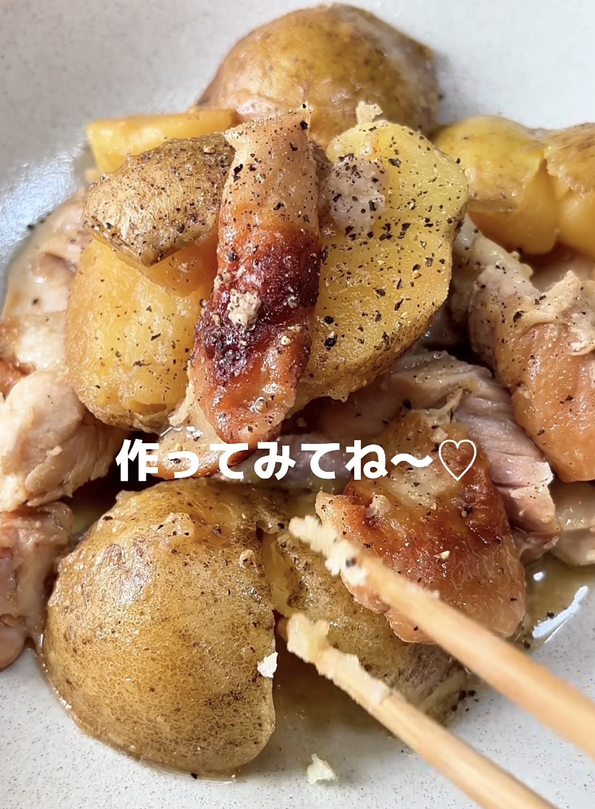 Bowl of roasted potatoes with crispy skins and chunks of meat; chopsticks lifting a piece for a bite, with a casual food photo vibe.