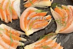 Onion petals wrapped around smoked salmon with dill, plated as a spring appetizer on a dark dish.
