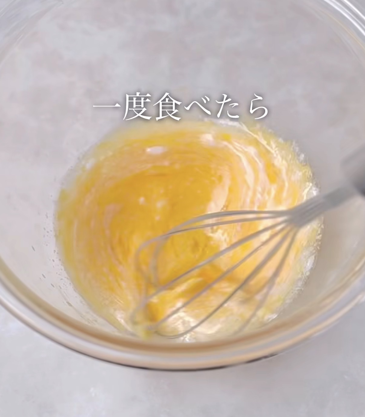 Whisk blending yellow batter in a glass bowl with Japanese text overlay reading '一度食べたら'.