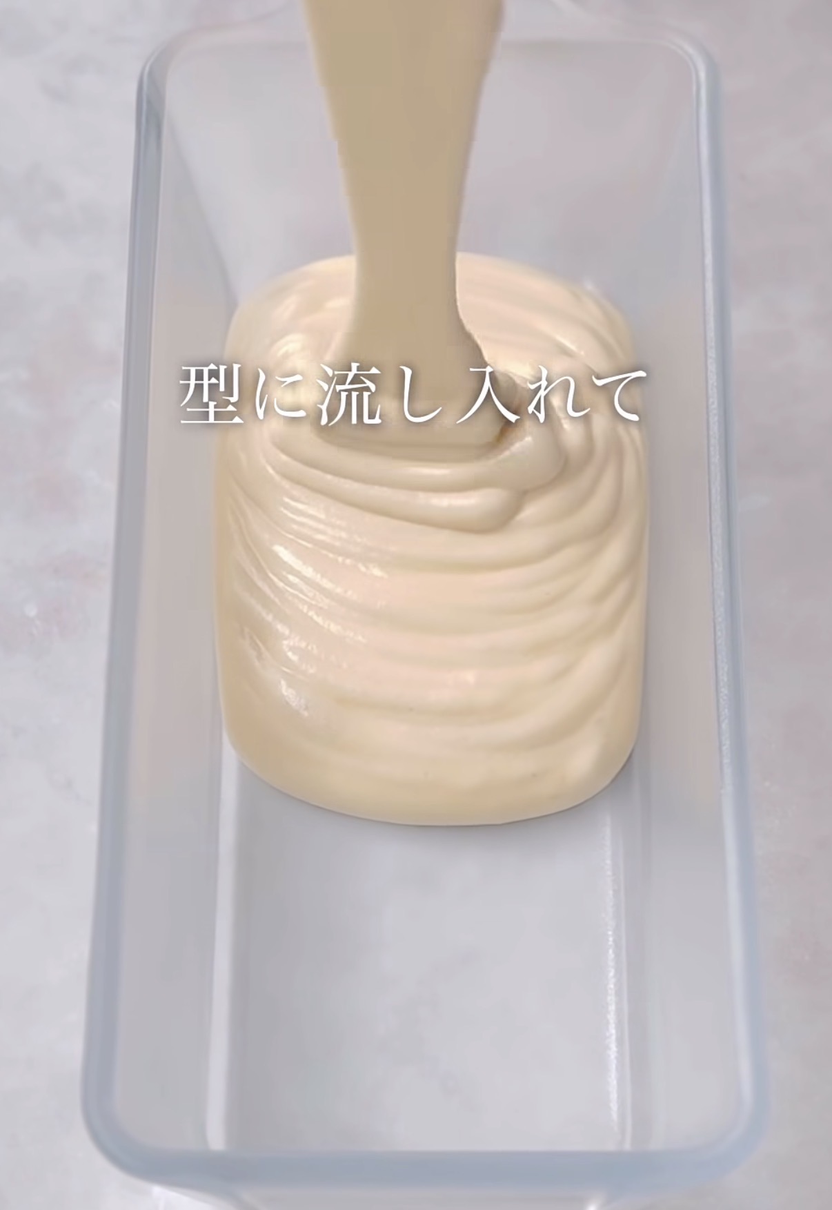 Creamy batter being poured into a rectangular loaf pan, filling it halfway.