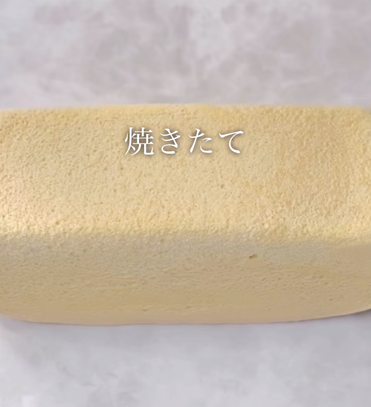 Freshly baked sponge cake roll with a parchment background and the Japanese word 焼きたて overlaid on top.