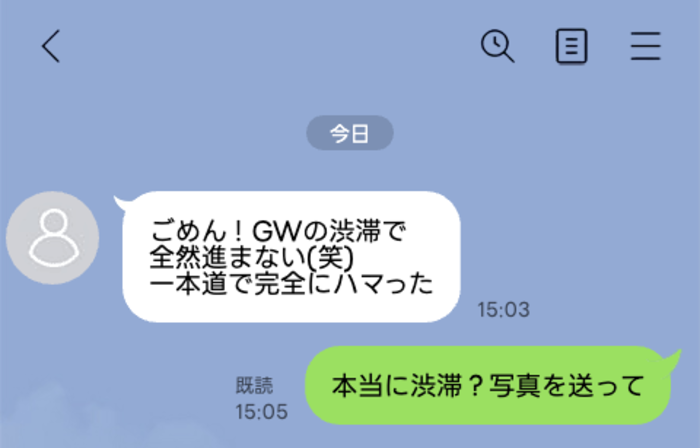 チャット画面。左側の白い吹き出しに『ごめん！GWの渋滞で全然進まない（笑）一本道で完全にハマった』、右側の緑色の吹き出しに『本当に渋滞？写真を送って』の会話が表示されている。背景は青色で上部に戻る矢印と検索・メニューアイコンが並ぶ。